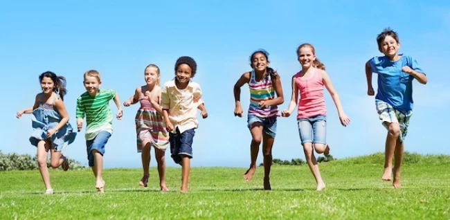 seven kids running on a field
