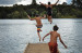 Three kids jumping into the water from a pier